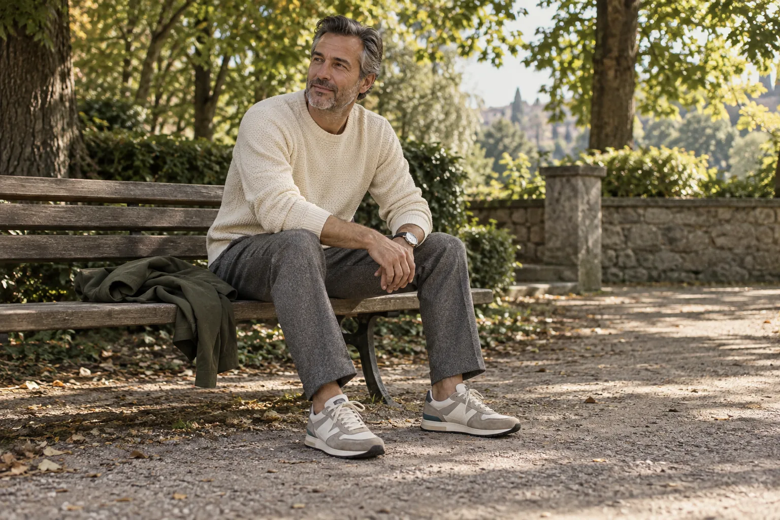 A seated man resting in a park, wearing neutral retro runners